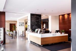 格拉茨Hotel Daniel Graz - Smart Luxury Near City Centre的一间带柜台和桌椅的餐厅