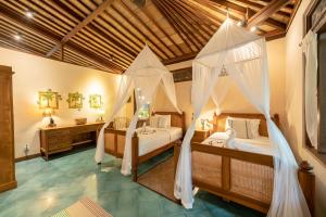 乌布Villa Uma Anyar- Joglo Uma的一间卧室配有两张带蚊帐的床