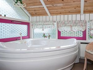 菲耶勒鲁普8 person holiday home in Glesborg的浴室设有粉红色的墙壁和窗户,配有白色浴缸。