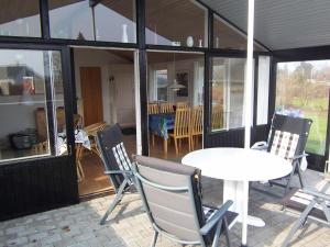 布罗艾厄4 person holiday home in Broager的庭院配有白色的桌椅、桌子和窗户。