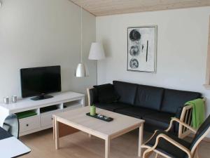 古兹耶姆6 person holiday home in Gudhjem的客厅配有黑色沙发和电视
