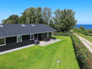 Rygård Strand16 person holiday home in Alling bro的一座黑屋顶和大院子的房子