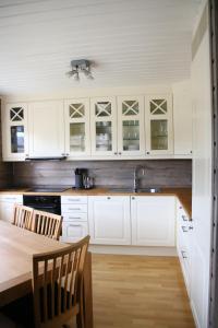 VossestrandMyrkdalen Resort Nedre Byggardslii apartment的厨房配有白色橱柜和木桌