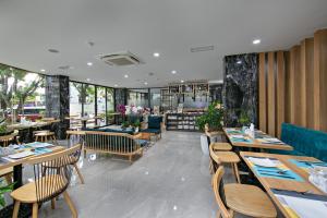 岘港Meliora Hotel & Apartment的一间带木桌椅的餐厅和一间酒吧