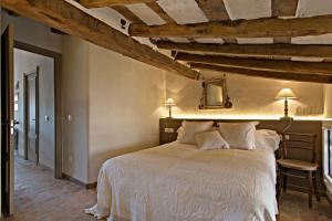 奥洛特El Jardinet de Sant Esteve的一间带白色床铺的卧室,位于带木制天花板的客房内。