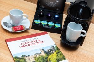 布兰登Brandon Hall Hotel & Spa Warwickshire的咖啡壶和一张桌子上的书,上面有咖啡杯