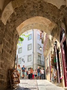 科英布拉Change The World Hostels - Coimbra - Almedina的一群人穿过建筑的拱门