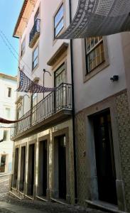 科英布拉Change The World Hostels - Coimbra - Almedina的街道上带阳台和遮阳伞的建筑