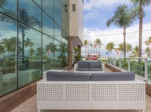 若昂佩索阿坦巴乌卢克索诺德酒店的享有一座配有沙发和棕榈树的建筑的景致。