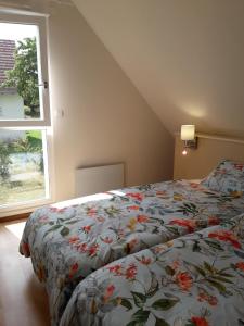 BernardswillerLes cerisiers的一间卧室配有一张带花卉棉被的床和窗户。
