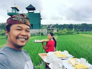 Tirtagangga谷米巴厘旅馆的把食物托盘与田野中的女人一起拿的男人