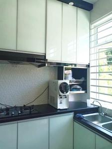 哥打巴鲁NRL's Cozy Guesthouse的厨房配有白色橱柜和台面上的微波炉