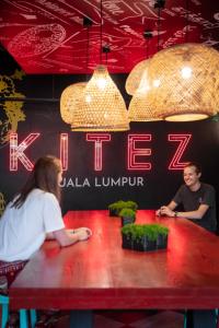 吉隆坡Kitez Hotel & Bunkz的坐在餐厅桌子上的男女