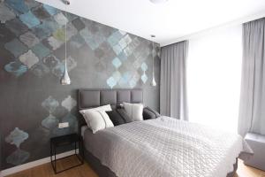 济夫努夫Apartament Gardenia Sea&Sun DZIWNÓW PRZY PLAŻY的一间卧室配有一张带灰色墙壁的床