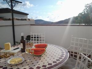埃尔博斯克CASA MARIA LUISA的阳台上的桌子上摆放着一瓶葡萄酒和水果
