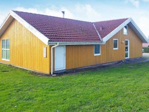 诺德堡12 person holiday home in Nordborg的绿色田野上红色屋顶的黄色房子