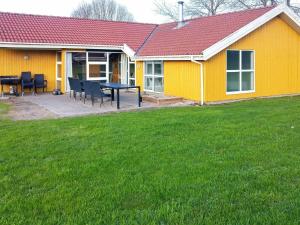 诺德堡12 person holiday home in Nordborg的院子里的黄色房子,配有桌椅