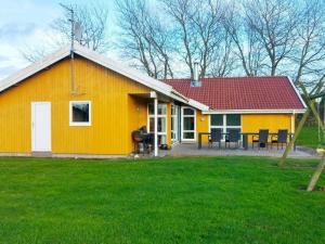 诺德堡12 person holiday home in Nordborg的一座黄色的房子,有红色的屋顶和院子