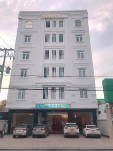Cao LãnhKhách sạn SAO NAM的一座白色的大建筑,前面有汽车停放