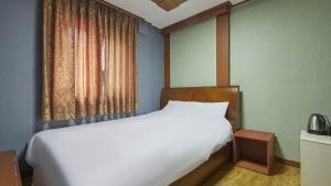 首尔柯姆康汽车旅馆的卧室设有一张白色大床和一扇窗户。