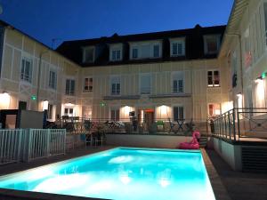 沙特拉永普拉日Boutique Hôtel d'Orbigny Chatelaillon - La Rochelle的一座游泳池,在晚上在建筑物前