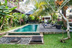 乌布Flamboyant Villa Ubud的后院的游泳池,配有桌子和长凳