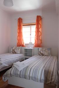 巴勒尔Baleal Holiday House的一间卧室设有两张床,窗户配有橙色窗帘