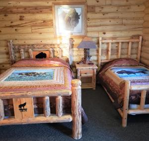ThayneWolf Den Log Cabin Motel and RV Park的小木屋内一间卧室,配有两张床