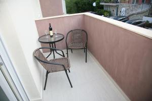 蒂瓦特Apartments Mira的阳台配有两把椅子和一张桌子及一瓶葡萄酒