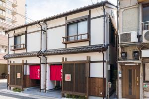 东京宿家千の里的一座带木门和红色衬衫窗户的建筑