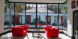 约翰内斯堡21翠鸟旅馆的一间设有两张红色椅子和一张桌子的房间