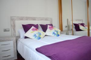 希洪Piso Céntrico y Moderno的一间卧室配有一张带紫色和白色枕头的床