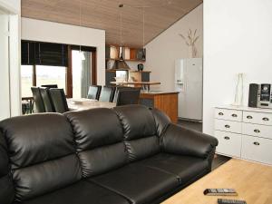 托斯明德8 person holiday home in Ulfborg的一间带真皮沙发的客厅和一间厨房