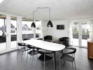 罗莫柯克比8 person holiday home in R m的一间配备有白色桌子和黑色椅子的用餐室