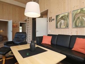 法贾德嘉德8 person holiday home in Ulfborg的客厅配有黑色沙发和桌子