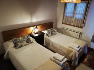 利亚内斯LA ALDEA的一间卧室设有两张床、一盏灯和一扇窗户。