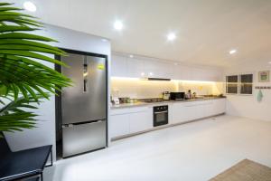 芭东海滩Rudi House的厨房配有白色橱柜和不锈钢冰箱