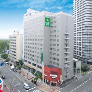 札幌Vessel Inn Sapporo Nakajima Park的一座白色的大建筑,上面有绿色的标志