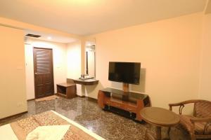 芭堤雅市中心卡特斯里楼酒店的客厅配有电视和桌椅