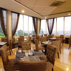 茂物茂物皇家酒店的餐厅设有桌椅和大窗户。