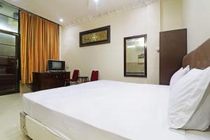 北干巴鲁Utama Syariah的卧室配有一张白色大床和电视。
