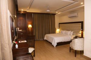 拉希迈尔汗Hotel One Rahim Yar Khan Club Road的酒店客房,配有一张床、一张桌子和椅子