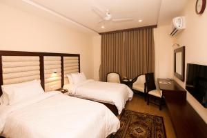 拉希迈尔汗Hotel One Rahim Yar Khan Club Road的酒店客房设有两张床和电视。