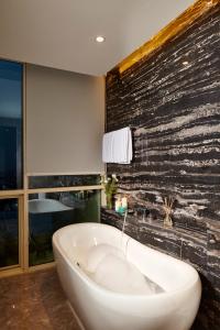 雅加达雅加达门腾辉盛庭国际公寓的带浴缸的浴室和石墙