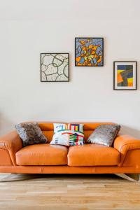 圣但尼Passion et détente by UTA HOUSE的客厅里一张橙色的沙发,上面有四张照片