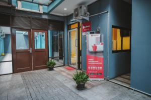 雅加达RedDoorz near RSUD Koja的门面,有门和盆栽的建筑物