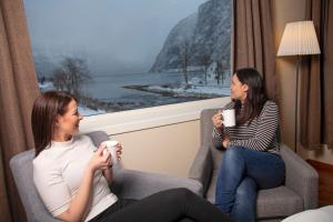 Høyanger奥伦酒店的坐在椅子上的两位妇女聊天喝咖啡