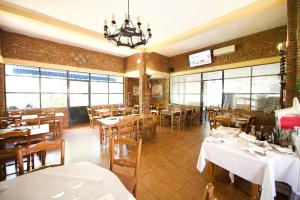 阿兰约兹Aranjuez Camping & Bungalows的餐厅设有白色的桌椅和窗户。