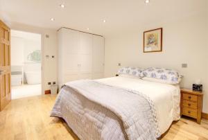 切尔滕纳姆Luxury Apartments - 39 Rodney Road Apartment的一间铺有木地板的白色卧室,配有一张床