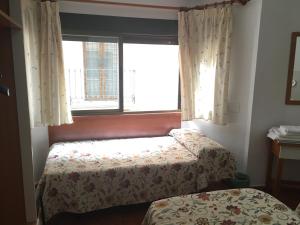 格拉纳达伊达尔戈酒店的一间卧室设有两张床和窗户。